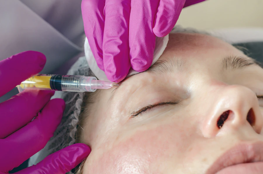 A practitioner administering an anti-wrinkle injection to a client’s forehead